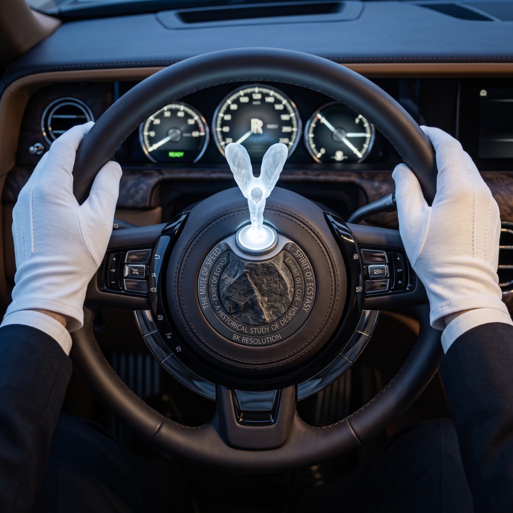 White-gloved chauffeur at a Rolls-Royce wheel with crystal Spirit of Ecstasy
